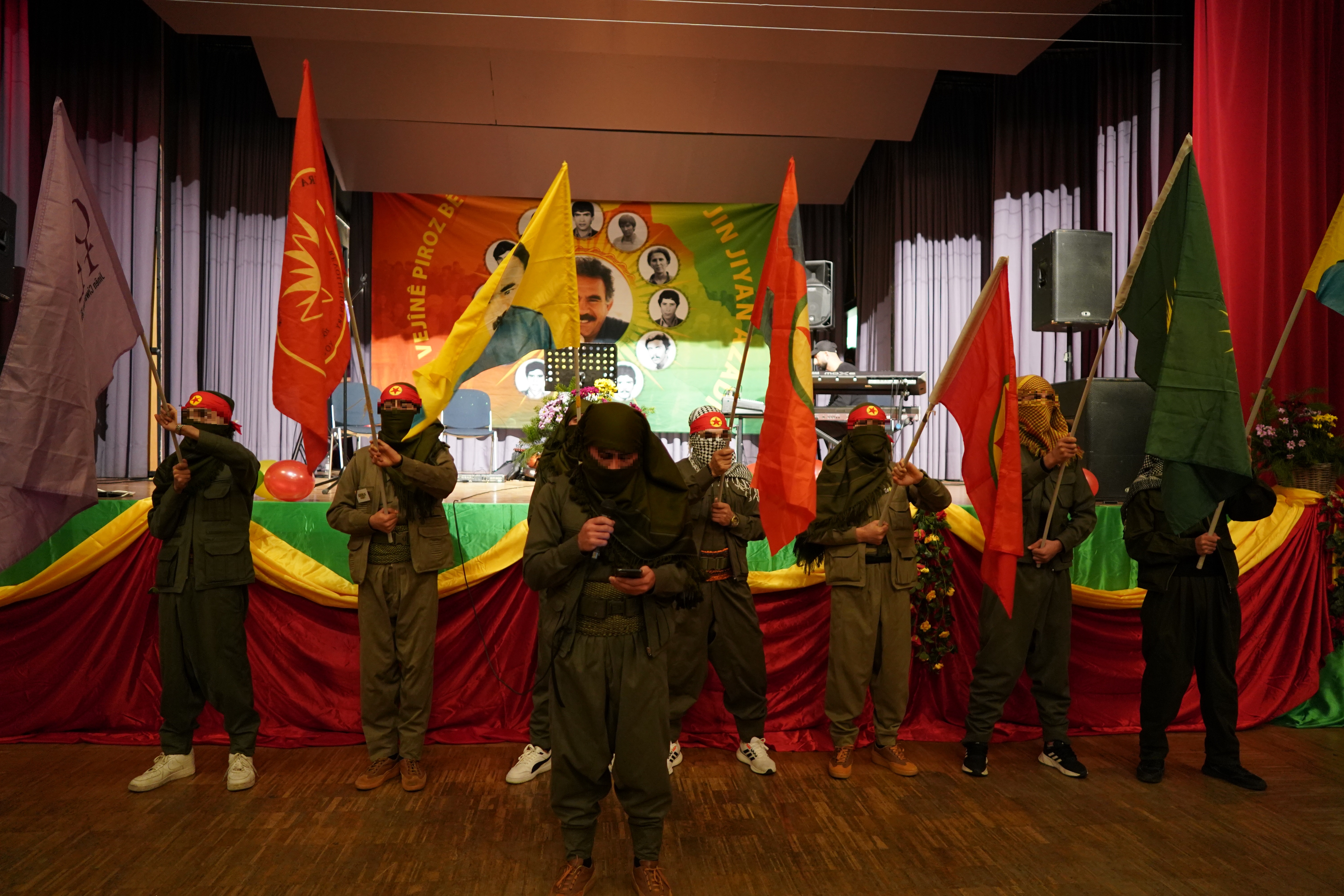 Jugendliche schwenken bei der PKK-Gründungsfeier im Stuttgarter Verein Fahnen mit PKK-Symbolik und einem Abbild ÖCALANs. Dies und ihre Stirnbänder mit PKK-Symbolik sowie die militärisch anmutenden Uniformen zeigen ihre ideologische Einbindung in die PKK-nahe Szene und die vorherrschende Gewaltorientierung.
